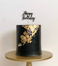 a black and gold birthday cake sitting on top of a table