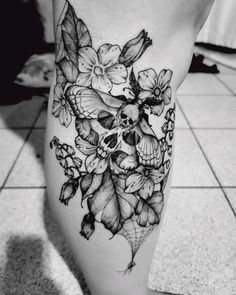 a black and white photo of a skull with flowers on it's side leg