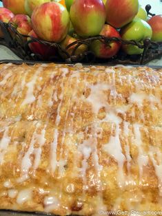 an apple pie with icing next to some apples