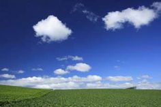 a green field under a blue sky with clouds