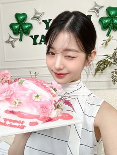 a woman holding a cake with pink frosting on it