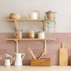 the shelves are filled with kitchen utensils and other items in front of a pink tiled wall