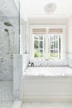 a bathroom with a large tub and two windows in it's center wall, along with marble tile flooring