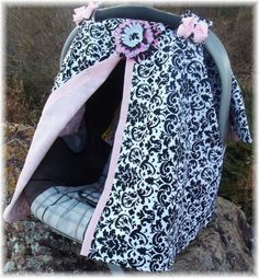 a black and white bag with pink flowers on the top is sitting on some rocks