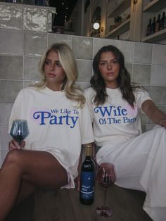 two women sitting next to each other holding wine glasses