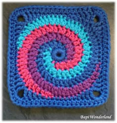 a crocheted square is shown in blue, pink and green with a spiral design