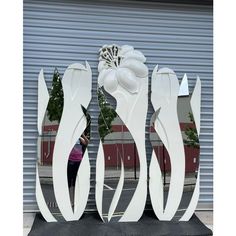 a large white sculpture sitting on top of a black table next to a building with a flower in it