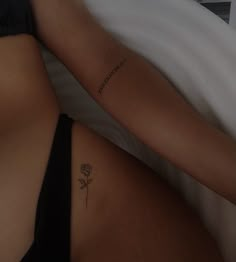 a woman laying in bed with her back turned to the camera and tattoos on her stomach