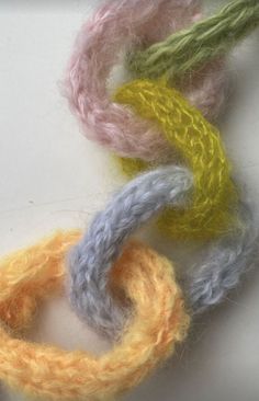 three different colored yarns on a white surface with one knot in the middle and another loop at the end