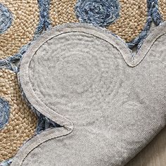 a heart shaped rug on top of a wooden floor next to a blue and white pillow