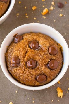 two white bowls filled with chocolate chip cookies on top of a gray countertop next to orange peels