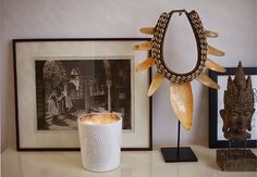 a table topped with pictures and sculptures on top of a white counter next to a framed photograph