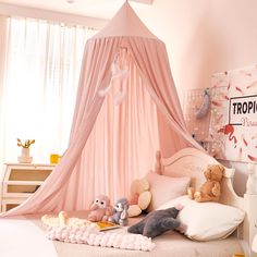 a pink canopy bed with stuffed animals on it in a child's playroom