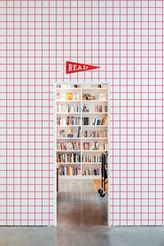 an open book shelf with books on it in front of a pink checkered wall