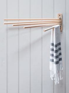 a towel hanging on a wall next to a pair of wooden clothes pins and a white striped towel