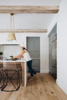 a woman standing at a kitchen island preparing food