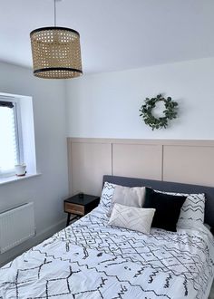 a bed with white and black comforter next to a window in a small room