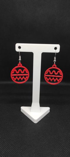 the red earrings are on display in front of a white stand with black fabric behind it