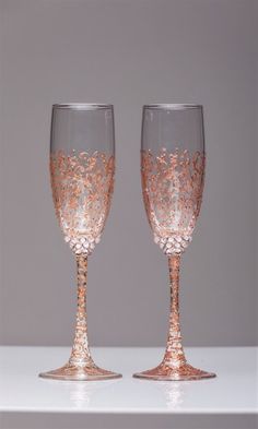 two wine glasses sitting side by side on a counter top, one is gold and the other is pink