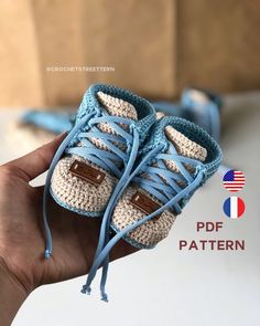 someone is holding up a crocheted baby booties with laces on them