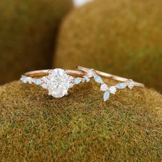 two engagement rings on top of a mossy surface, with one diamond in the middle