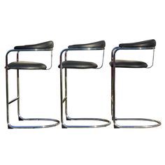 three black leather chairs with chrome frames on each side and one has a curved seat