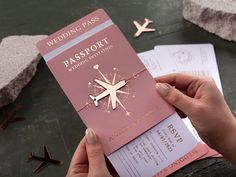 a person holding up a pink passport on top of a table next to other items