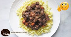 a white plate topped with pasta and meat covered in gravy next to an emoticive smiley face