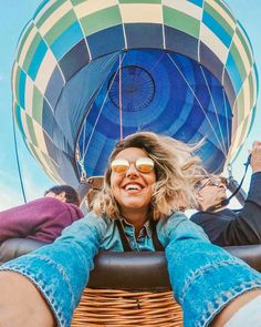 a woman sitting in a hot air balloon with her feet up on the ground and smiling