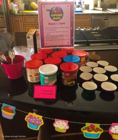 cupcakes are displayed on a table in front of a sign