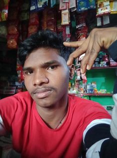 a man sitting in front of a store with his hand on the top of his head