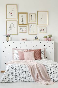 a bed with black and white polka dots on it, surrounded by framed pictures above the headboard