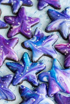 purple and blue decorated cookies sitting on top of a white plate with stars in the middle