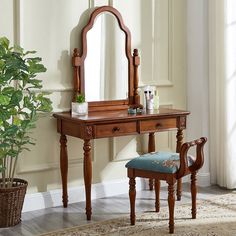 a wooden dressing table with mirror and stool next to a potted plant on the floor