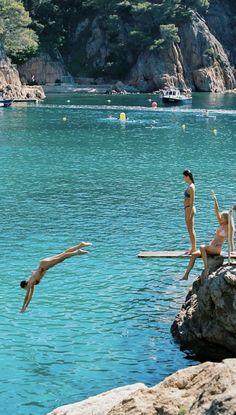 three people jumping into the water from rocks