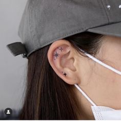 a woman wearing a baseball cap has a small star tattoo on her left side ear