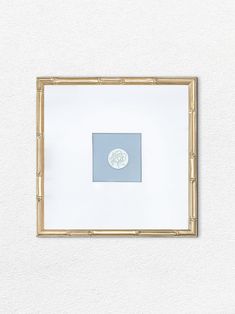 a white wall with a gold frame hanging on it