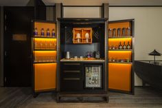 a small bar with orange shelves and bottles on the wall, in a hotel room