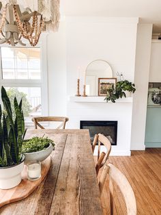 a dining room table with some plants on it and a fireplace in the back ground