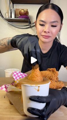 a woman sitting at a table with food in front of her and holding a cup