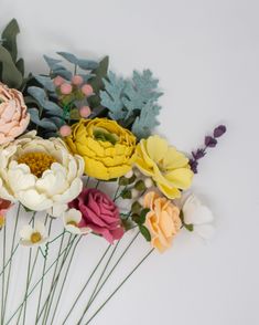 a bunch of flowers sitting on top of each other in front of a white wall