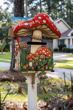 a mailbox with mushrooms painted on it in front of some trees and bushes near a house