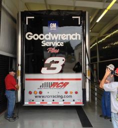 two men standing in front of a large truck with the words goodwren service painted on it