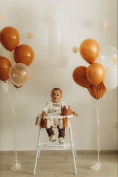 a baby sitting in a chair surrounded by balloons