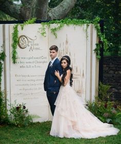 a bride and groom standing in front of a sign