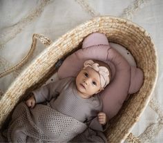 a baby laying in a basket on top of a bed