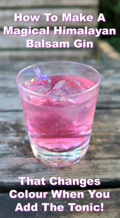 a glass filled with pink liquid sitting on top of a wooden table