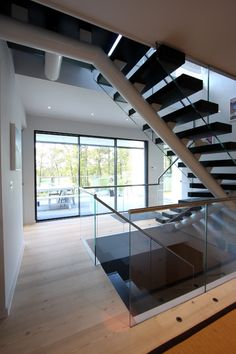 a modern staircase with glass railing and wood flooring