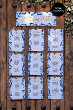 wedding seating cards with blue leaves and gold foil on them, hanging from a wooden wall