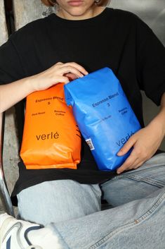 a person sitting down with two bags on their lap and one bag in the other hand